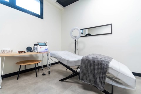 Modern clinic room featuring a laser device, protective eyewear, and a treatment bed ready for