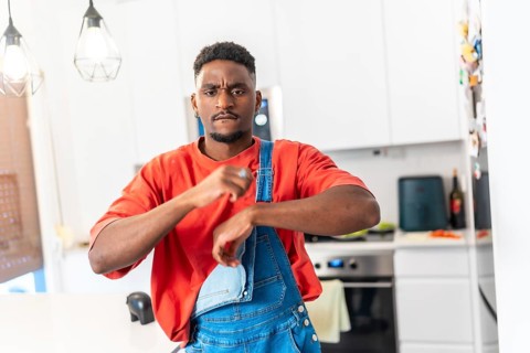 Young black man wearing casual clothes is dancing urban style in a modern kitchen, expressing his