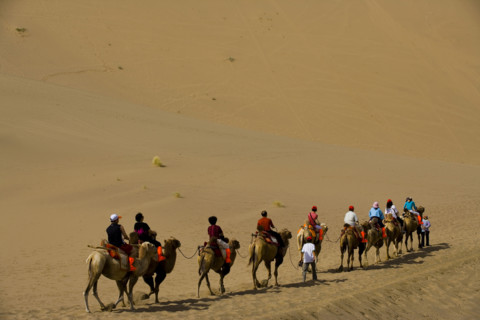 A Group of People Riding Camels in the Desert