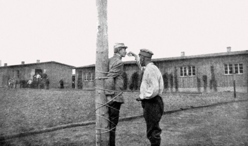 Première Guerre Mondiale. Au camp de Zwickau, un prisonnier français, lié au poteau, reçoit un verre d'eau d'un prisonnier roumain