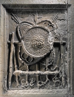 Frise de l'Art de la Guerre : Bélier fixé à un support en forme de tréteau et un bouclier rond superposé à deux boucliers ovales