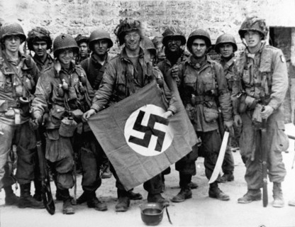 Des parachutistes américains posent avec un drapeau nazi capturé, 1944