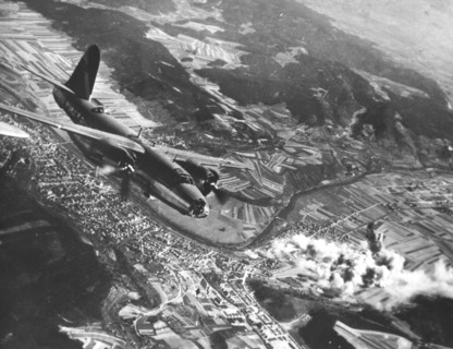 A B-26 swoops down over a blazing German ordnance depot in Rudolstadt (Germany) April 10, 1945