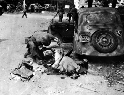 Un soldat du U.S Army Medical Corps traite un officier allemand près de Chartres (France). août 1944