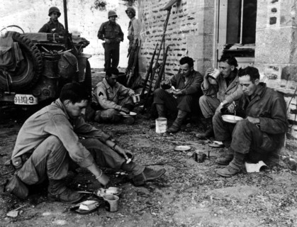 US soldiers eat hot meal in a street of Perriers (France) summer 1944