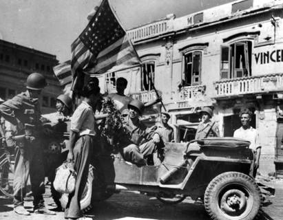 A Messine, en Sicile, les civils offrent des fleurs aux soldats américains.
(24 août 1943)