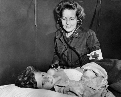 Infirmière de l'U.S. Army soignant un enfant français blessé en Normandie.
 (Eté 1944)