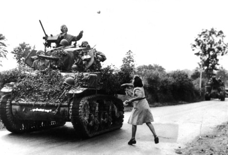 Une jeune fille jette des fleurs aux soldats américains à St-Pois,  août 1944