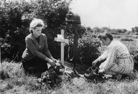 Deux habitantes de Carentan fleurissent la tombe d'un parachutiste américain