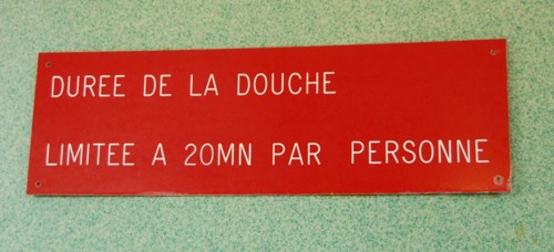 Ein Hinweisschild mit der Aufschrift: "Duree de la douche limitee a 20...