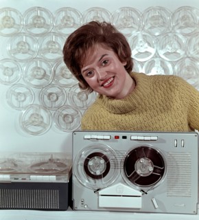 Eine Frau präsentiert das RFT Bandgerät BG 26-1, aufgenommen um 1963.