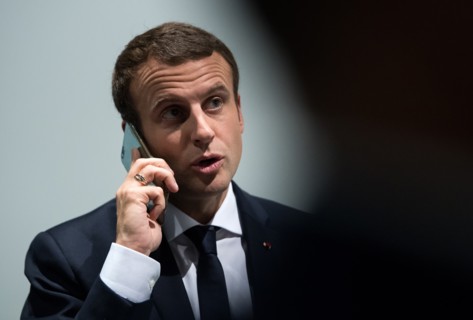 Emmanuel Macron talks on his telephone as he walks along a corridor in the exposition halls in Hamburg