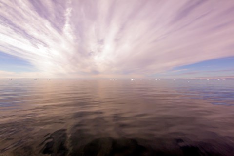 Sun rays through clouds above the ocean, Greenland