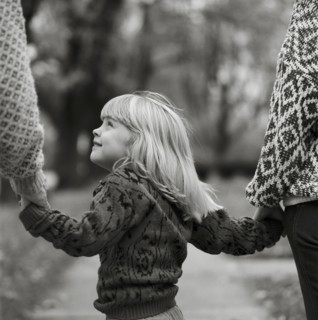 Young Blonde Girl Holding Parents' Hands