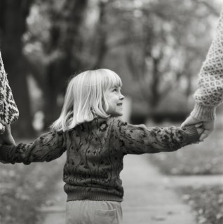 Young Blonde Girl Holding Parents' Hands