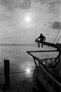 Sailor Sitting on Pole on Sailboat
