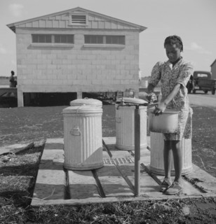 Young Girl Filling Pot with Water, Okeechobee Migratory Labor Camp, Belle Glade, Florida, USA, Marion Post Wolcott for Farm Security Administration, June 1940