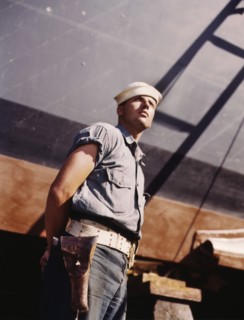 Coast Guard Sentry Standing Watch over New Torpedo Boat Under Constructions at Shipyard, Higgins Industries, Inc., New Orleans, Louisiana, USA, Howard R. Hollem for Office of War Information, July 194...