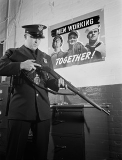 Sentinel Inspecting Rifle as he Keeps Vigil Against Saboteurs at Factory Converted to War Production, White Motor Company, Cleveland, Ohio, USA, Alfred T. Palmer for Office of War Information, Decembe...