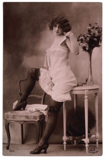 French Lingerie Model Leaning on Table With One Leg Raised on Chair, 1920