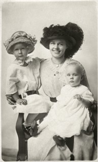 Woman With Dark Hat Seated with Two Children, one with Hat, Portrait, circa 1915