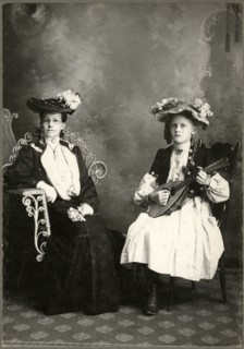Seated Older Woman  in Long Dress and Hat Sitting Next to Young Girl Holding Lute, Cabinet Card, circa 1911