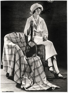 Fashionable Young Woman in White Jersey Sport Costume with Plaid Coat-Cape, Holding Tennis Racquet, Portrait, circa 1922