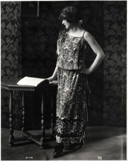 Fashionable Woman in Dinner Dress of Silk Crepe and Satin with an Embroidered Design of Tropical Birds, and Hat, Portrait, circa 1922