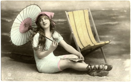 Seated Woman in Blue Swim Dress Holding Parasol next to Beach Chair, circa early 1900's
