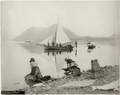 Two Women Doing Laundry at Shore of Lake Maggiore with Sailboat and Sasso di Ferro Mountain in Background, Lombardy, Italy, circa 1880