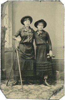 Portrait of Two Young Adult Women, Both Standing in Hats and Long Skirts with Poles, Rings and  Weights, circa 1870