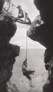 Photographer, Emery or Elsworth Kolb, Suspended on Climber's Rope in Crevasse and Photographing Canyon Wall as Another Man Straddles Cliff Opening while Holding the Rope, Grand Canyon, Arizona, USA, b...