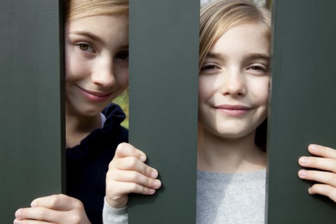 Two Smiling Girls Behind Fence