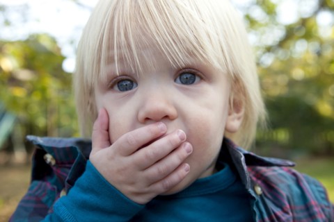 Young Blonde Boy With Hand Over Mouth