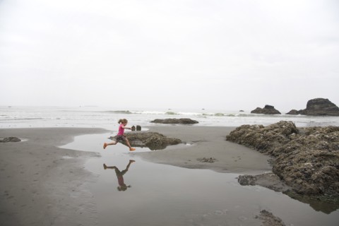 Girl Jumping Over Tidal Pool on Beach