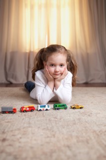 Girl Portrait on Floor with Toy Cars and Trucks