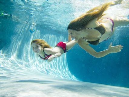 Mother and Daughter Swimming Underwater in Pool