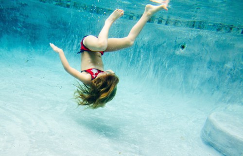 Girl Floating Upside Down Underwater in Pool