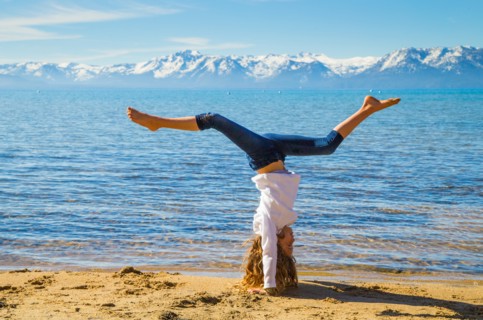 Young Girl Doing Hand Stand on Beach with Sierra Mountains in Background, Lake Tahoe, Glenbrook, Nevada, USA