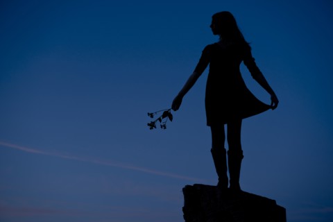 Girl Standing on Rock Holding Flowers, Silhouette