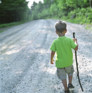 Young Boy with Stick Walking Down Path