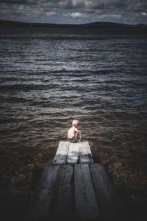 Young boy Playing With Rope at End of Dock on Lake