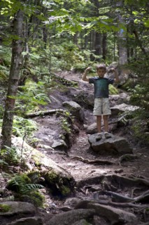 Young Boy Flexing Arm Muscles on Path in Woods