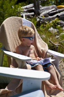 Young Boy in Sunglasses Sucking on Lollipop in Adirondack Chair