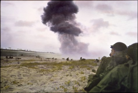 U.S. Soldiers Protect themselves from Enemy Fire as 88mm Shell from German Howitzer Explodes in Background, Utah Beach, Normandy, France, June 1944