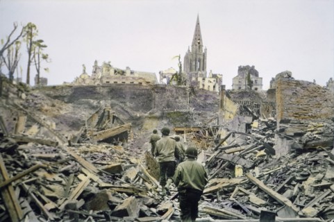American Infantry Patrol Walking Through Ruins of the French Town, Saint-Lo, after it was Captured from the Germans, South Tower of Church of Notre Dame de Saint-Lo in Background, Battle of Normandy, ...