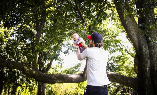 Father Holding up Infant Son in Park