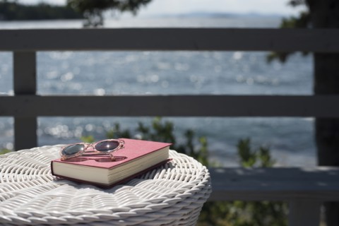 Book and Sunglasses on Wicker Table on Lakeside Deck