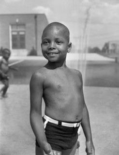 Young Boy Cooling off in the Community Sprayer, Frederick Douglass Housing Project, Anacostia Neighborhood, Washington DC, USA, Photograph by Gordon Parks, June 1942