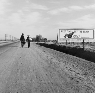 Rear View of Two Men Walking toward Los Angeles, California, USA, on Dirt Road near Billboard that says "Next Time Try the Train. Relax.", Dorothea Lange, U.S. Farm Security Administration, March 1937